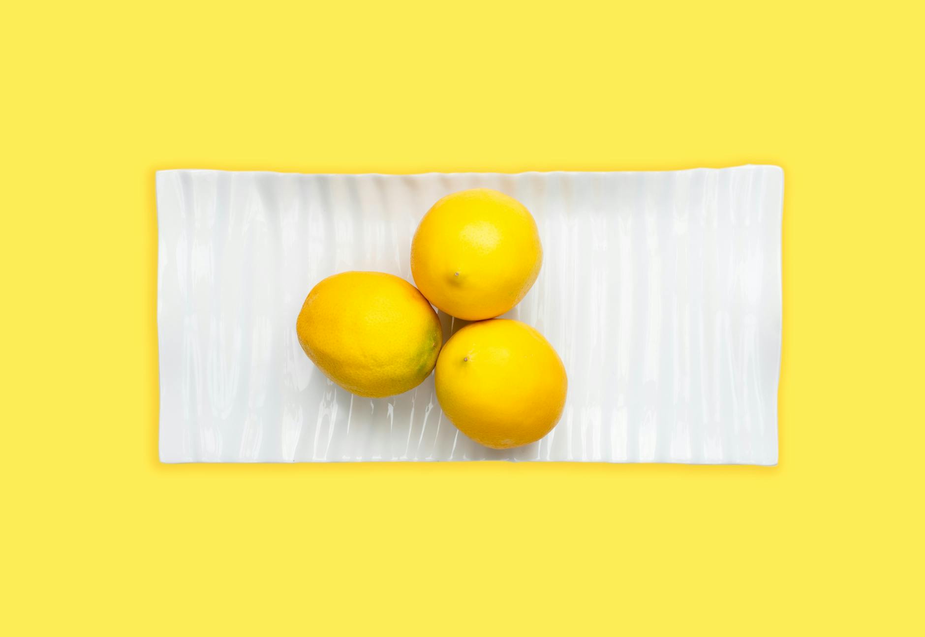 Fresh lemons on white plate with yellow background, symbolizing natural pleasure and self-discovery