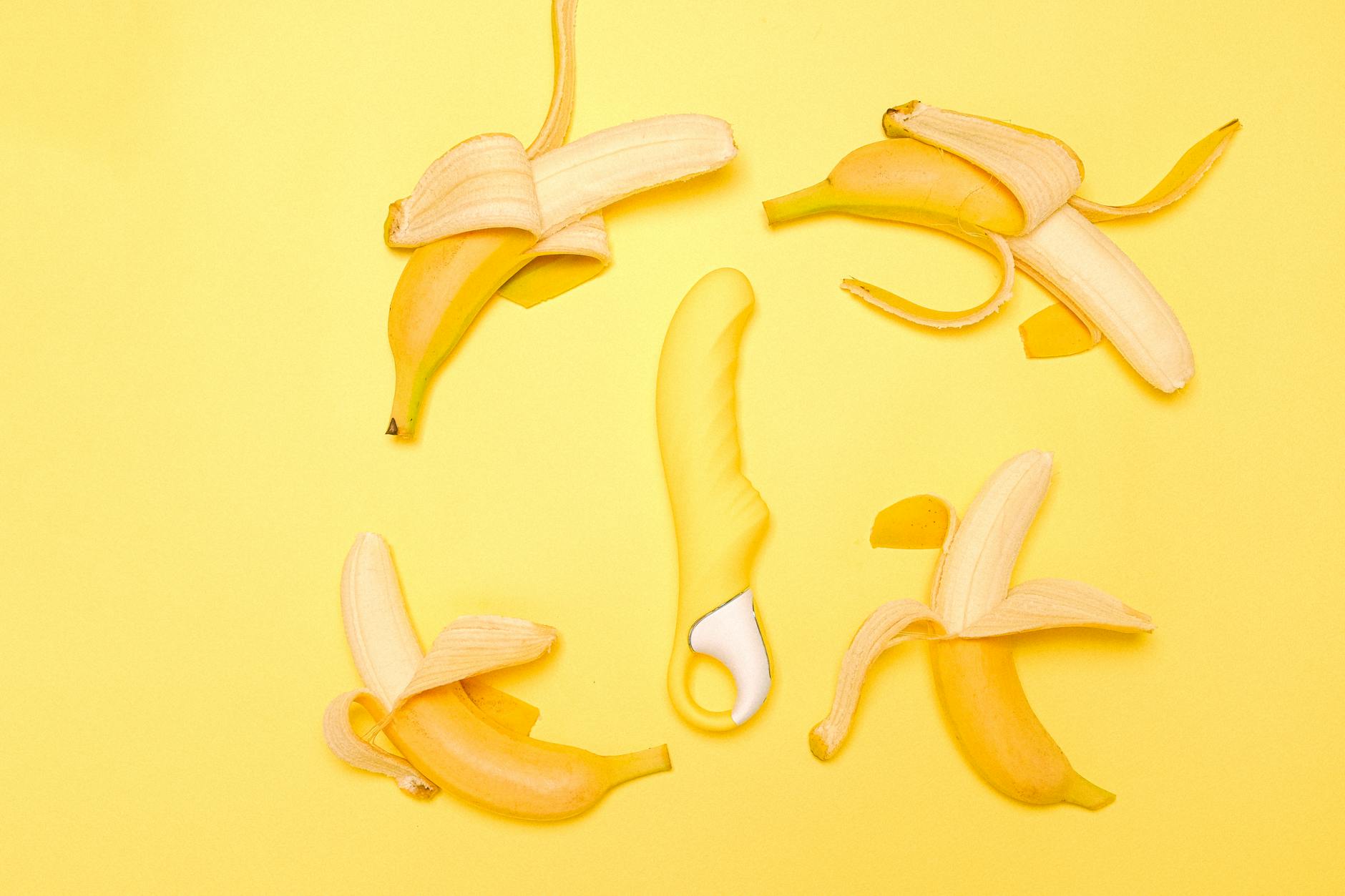 Yellow silicone lemon vibrator surrounded by fresh peeled bananas on a bright yellow background, symbolizing renewed sensation and sensitivity recovery.