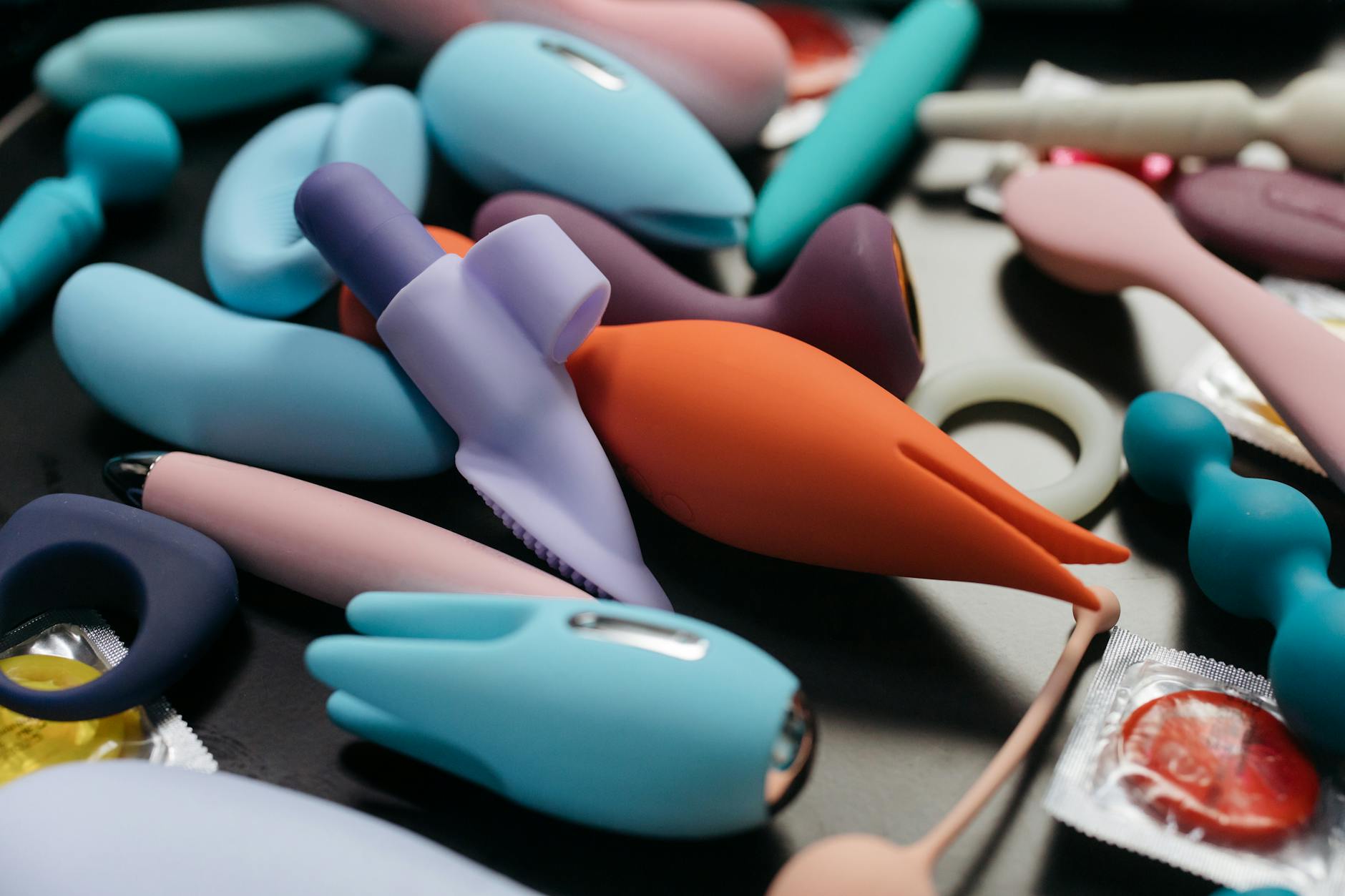 A hand holding an orange vibrator against a minimalistic purple backdrop, showcasing modern sensuality