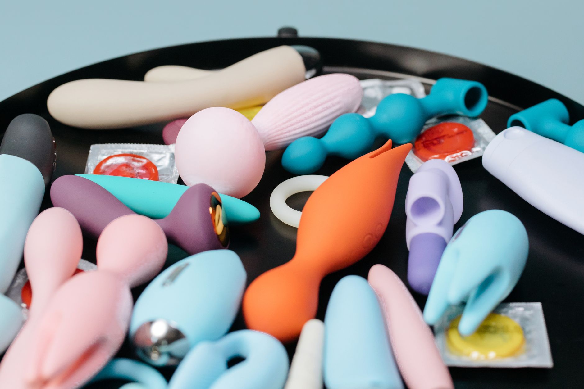 Collection of colorful clitoral vibrators on a black surface, representing diverse pleasure options during recovery