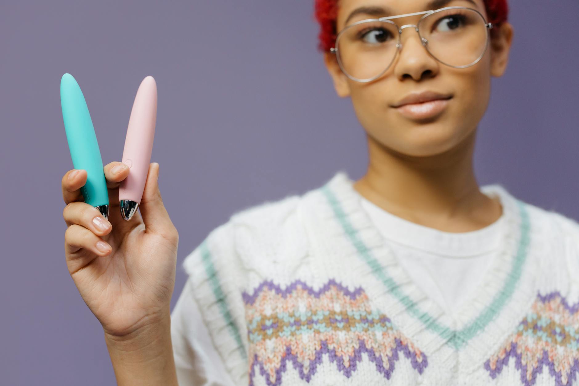 A woman holding colorful vibrators against a purple background, representing choice and self-care after loss.