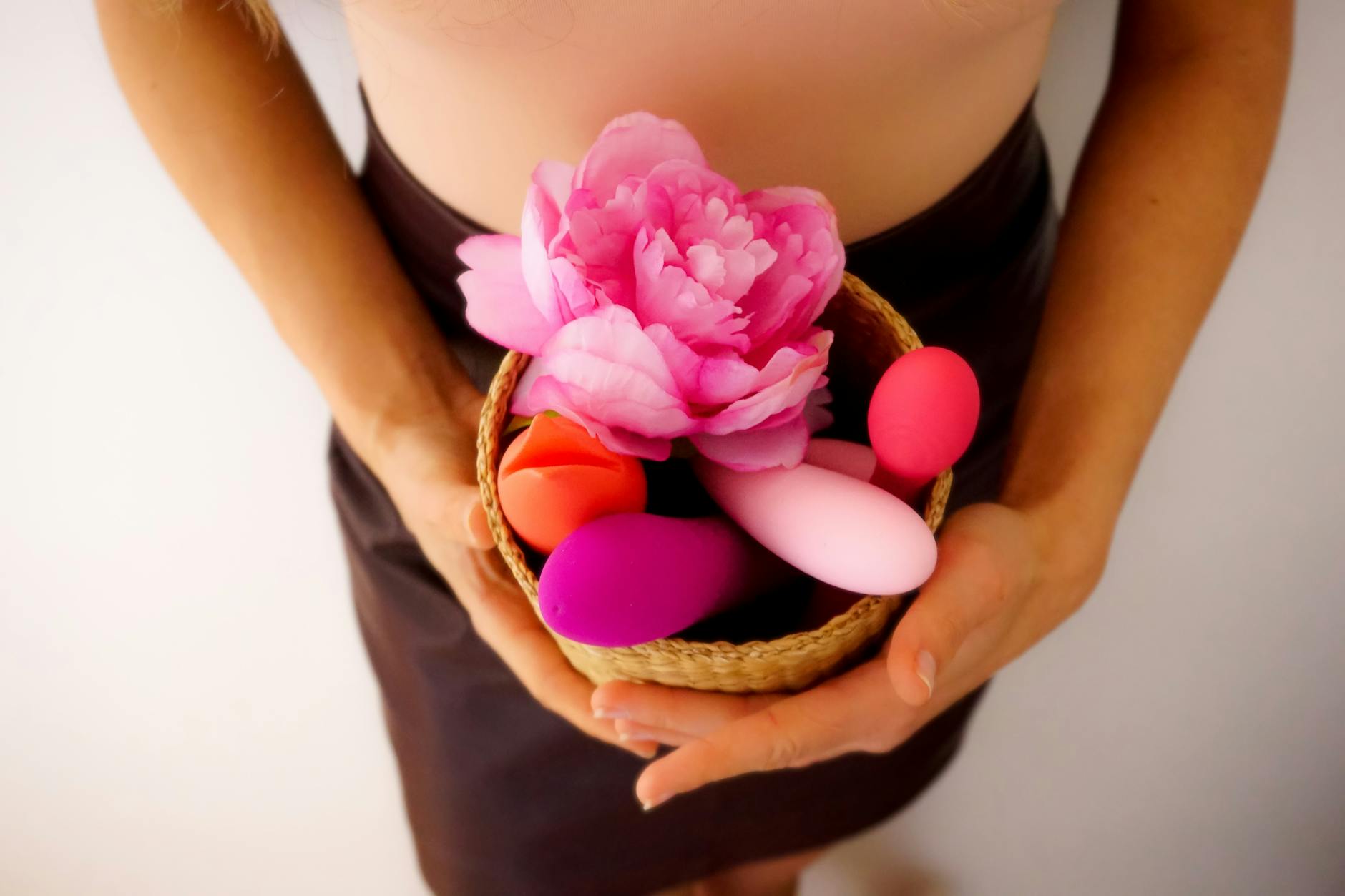 A hand holding an orange vibrator against a minimalistic purple backdrop